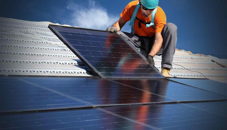 Instalator przy panelach fotowoltaicznych na dachu – zdjęcie poglądowe