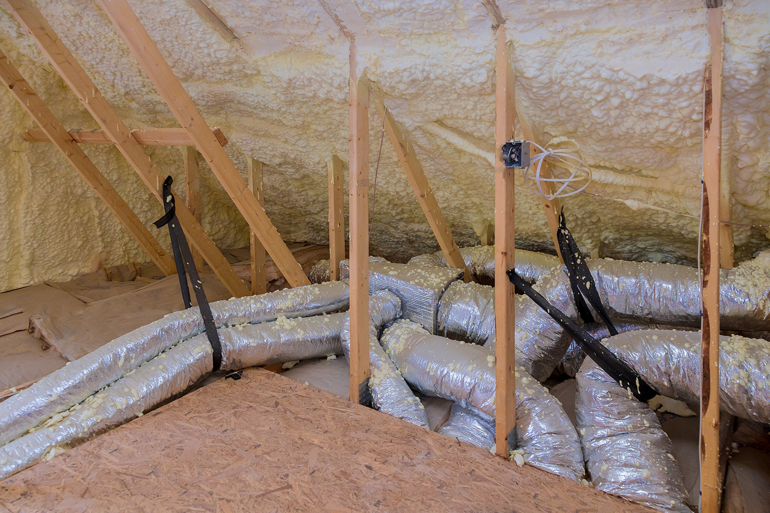 House air ventilation pipes in silver insulation material on the attic with a heating system