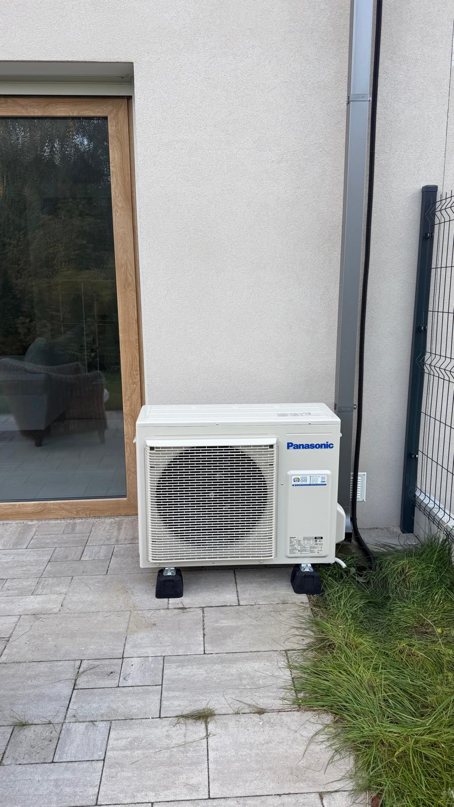 Zdjęcie przedstawia zamontowany i zabezpieczony folią panel/nawiewnik klimatyzacji kanałowej Haier nad otworem drzwiowym. Widoczne są świeżo zagipsowane/zatynkowane bruzdy z poprowadzonymi instalacjami elektrycznymi i chłodniczymi w pomieszczeniu podczas prac wykończeniowych.