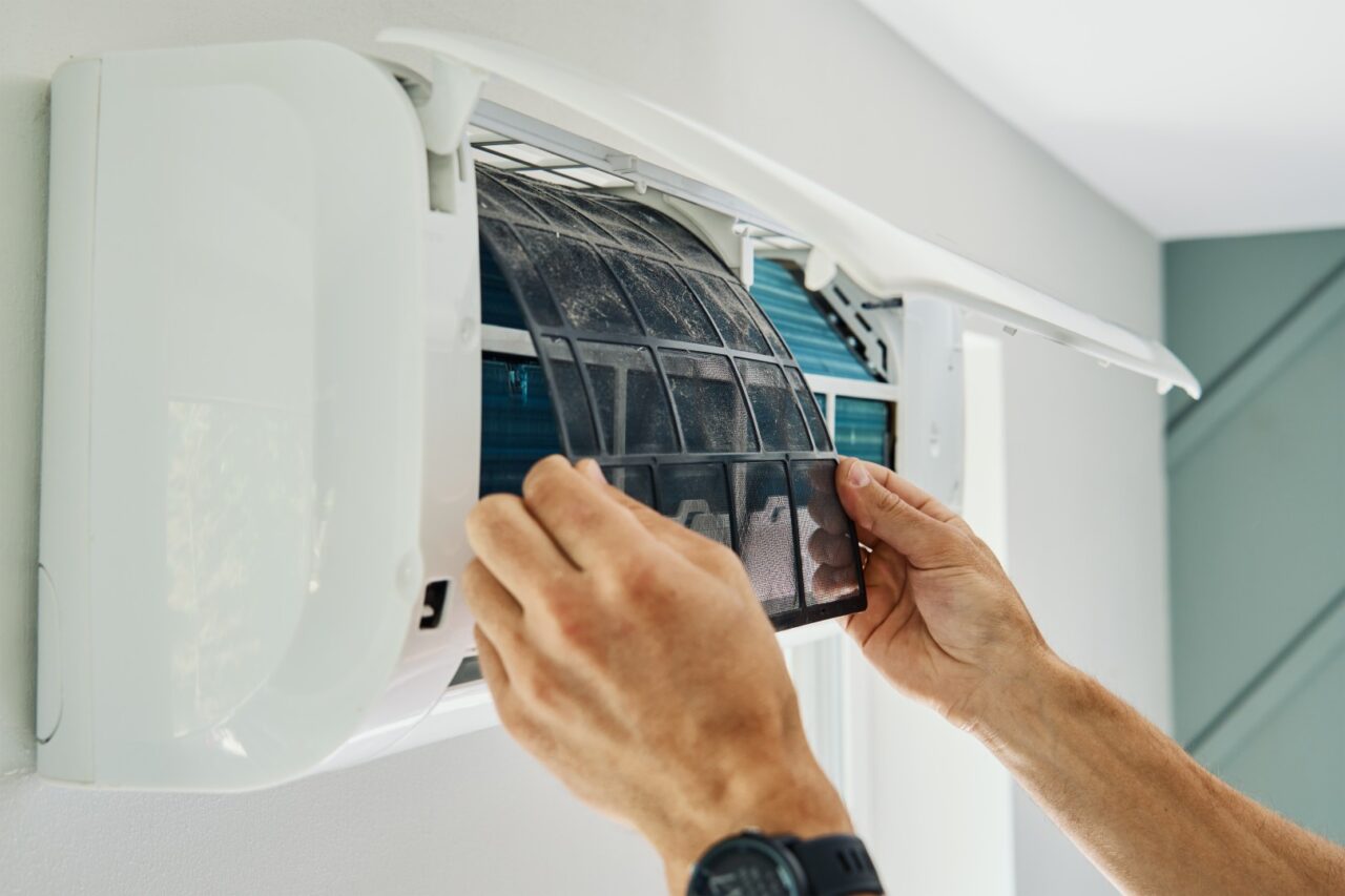 Dłonie technika czyszczące zabrudzony filtr w klimatyzatorze ściennym