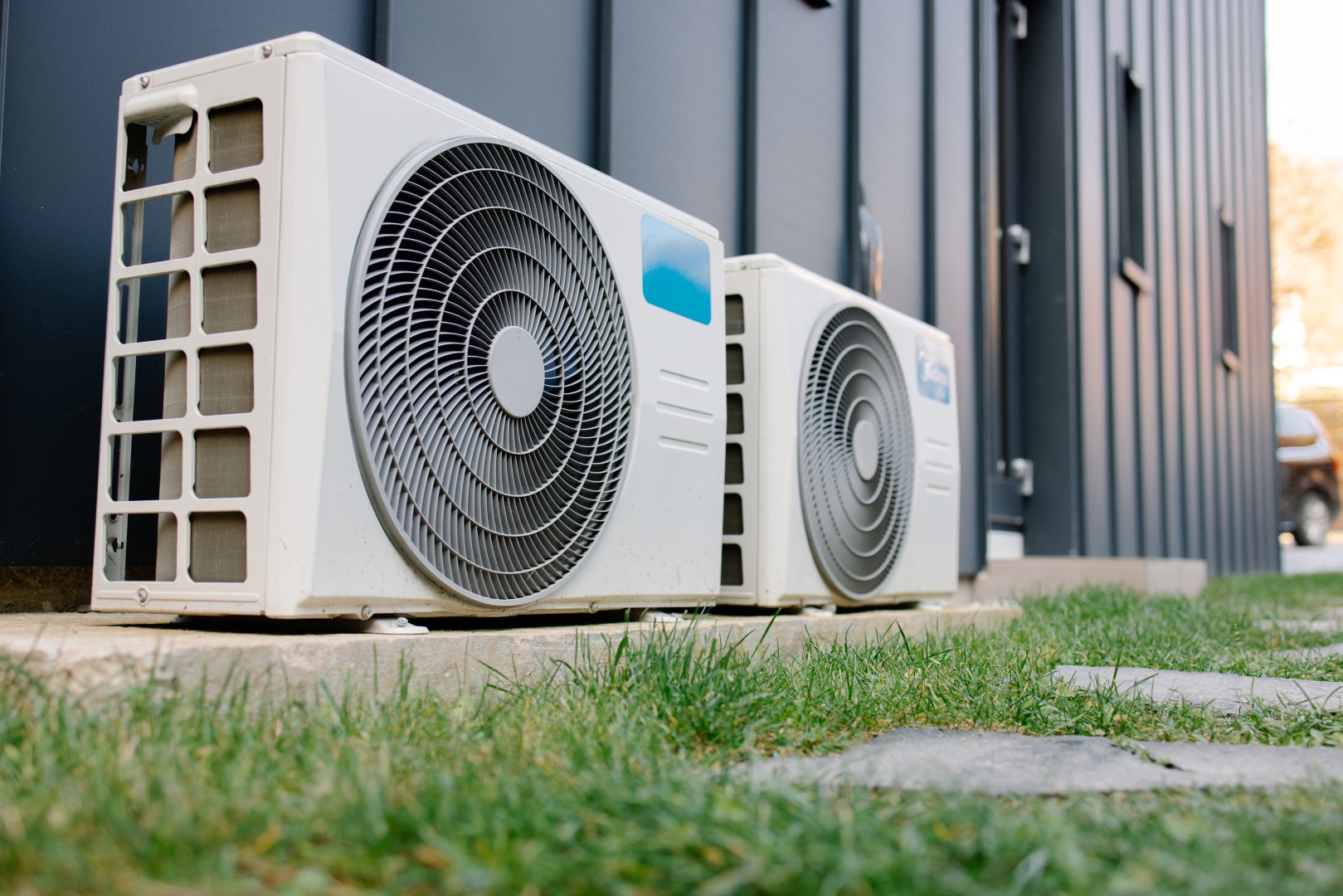 Klimatyzacja w bloku – czy potrzebujesz zgody wspólnoty i jak ją uzyskać 1 Dwie jednostki zewnętrzne klimatyzacji zamontowane przy nowoczesnym budynku z ciemną elewacją