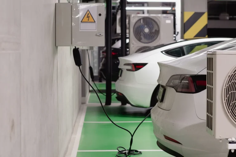 Samochody elektryczne ładowane z wallboxów w hali garażowej budynku